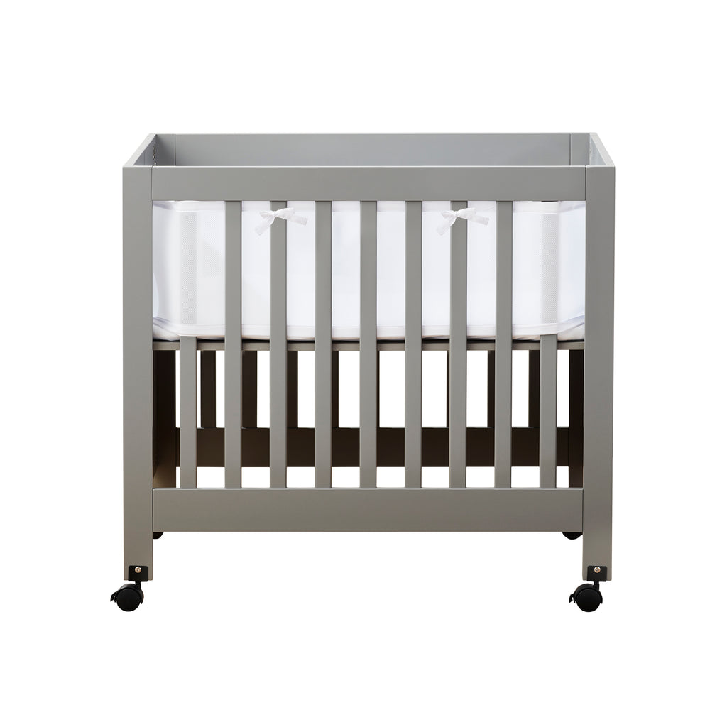 Front view of BreathableBaby Breathable Mesh Crib Liner for Mini/Portable Cribs on a crib in White on white background