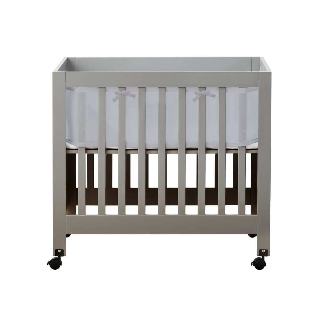 Front view of BreathableBaby Breathable Mesh Crib Liner for Mini/Portable Cribs on a crib in Gray on white background