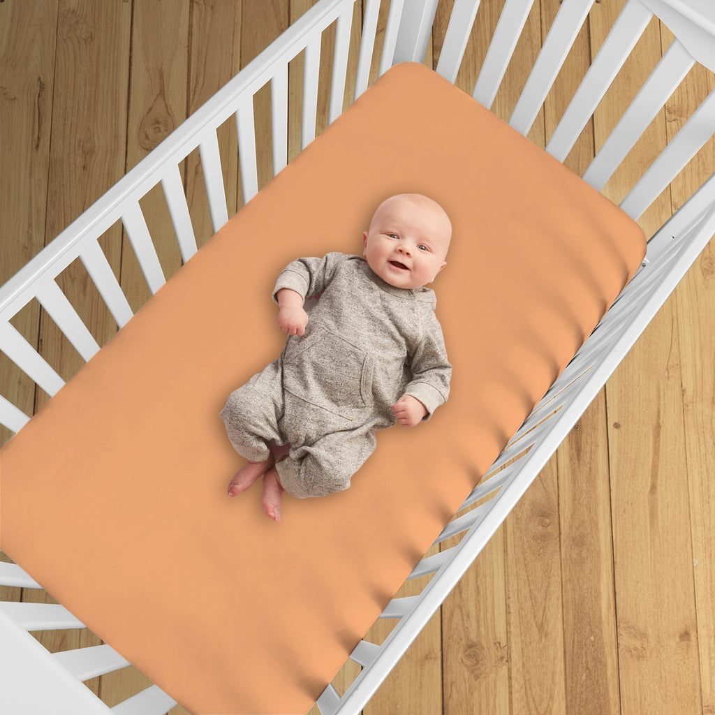 BreathableBaby All-in-One Fitted Sheet & Waterproof Cover for Crib Mattresses in Coral Shown in Crib